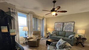 A living room with a sofa, armchairs, a coffee table, and a ceiling fan. There are two side tables with lamps and a large window with curtains. - Updated Butler's Treasure Island,new master bath! Beach Service for 2 Included! (Panama  City  Beach)