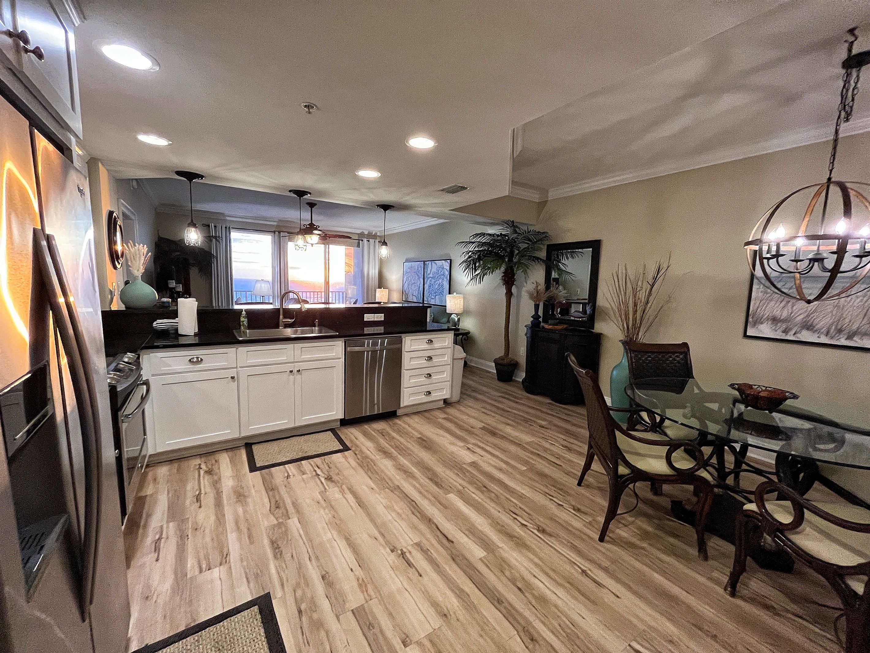 A spacious kitchen with white cabinets, a dishwasher, and a dining area with a glass table and chairs.