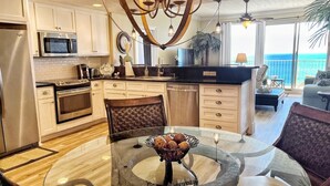 A modern kitchen with a central island, stainless steel appliances, and a dining area with a glass table and chairs. - Updated Butler's Treasure Island,new master bath! Beach Service for 2 Included! (Panama  City  Beach)