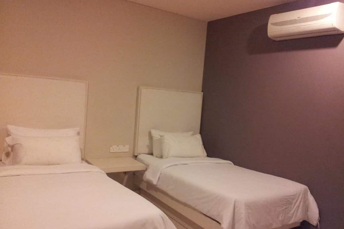 Hotellihuone, jossa on kaksi erillistä sänkyä, yöpöytä ja seinälle asennettu ilmastointilaite.
