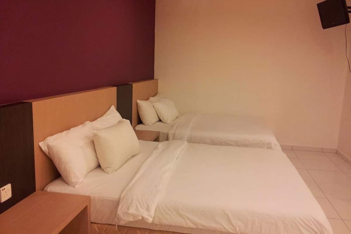 Hotellihuone, jossa on kaksi sänkyä, puinen pääty, seinälle asennettu televisio ja yöpöytä.