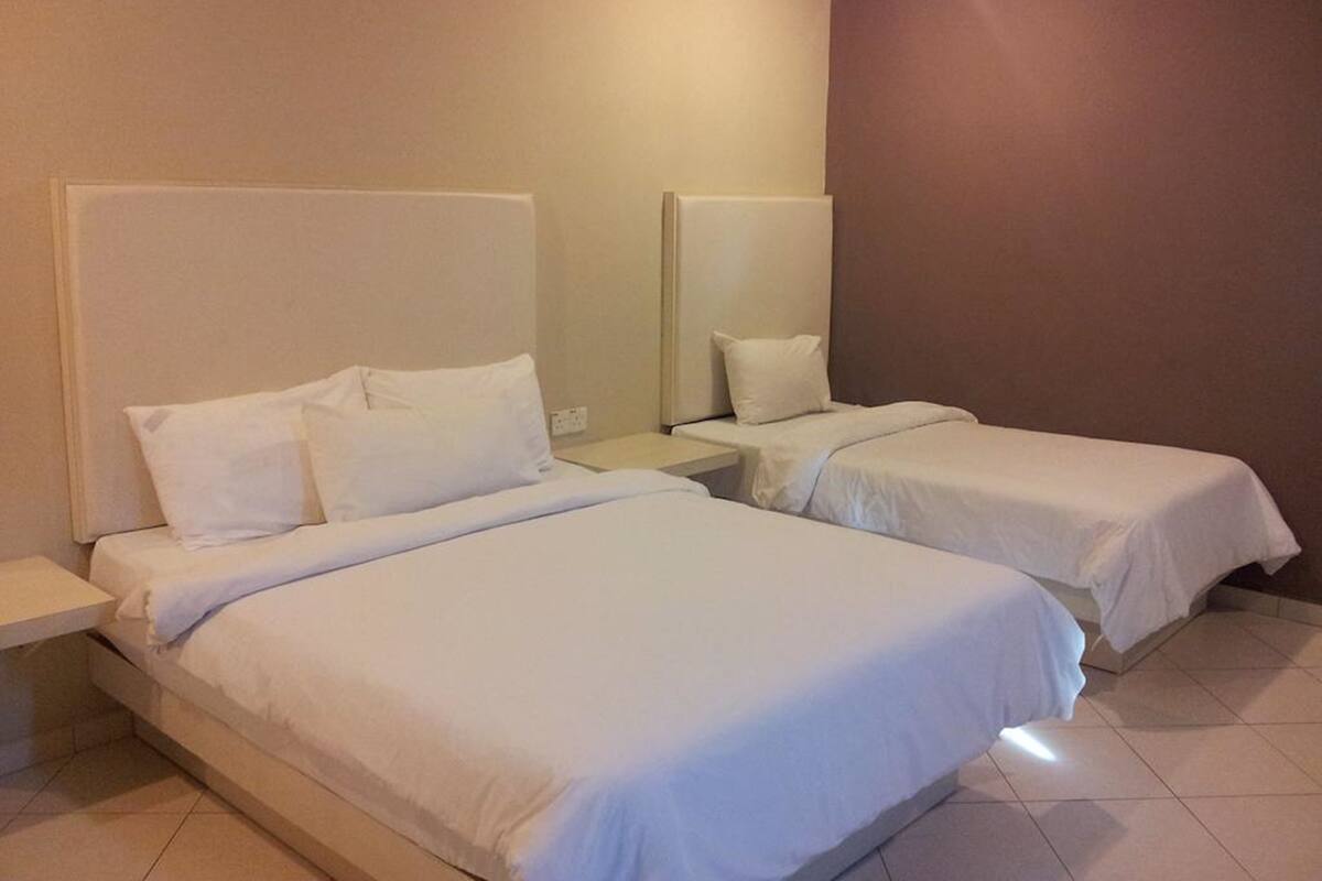 Hotellihuone, jossa on kaksi erillistä sänkyä, yöpöytä ja peili.