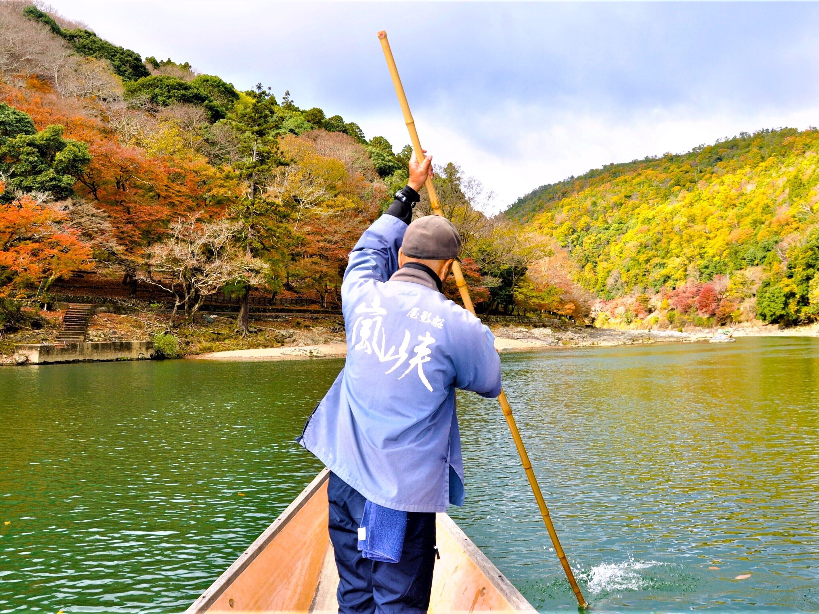 A person in a canoe on a river surrounded by autumn foliage.