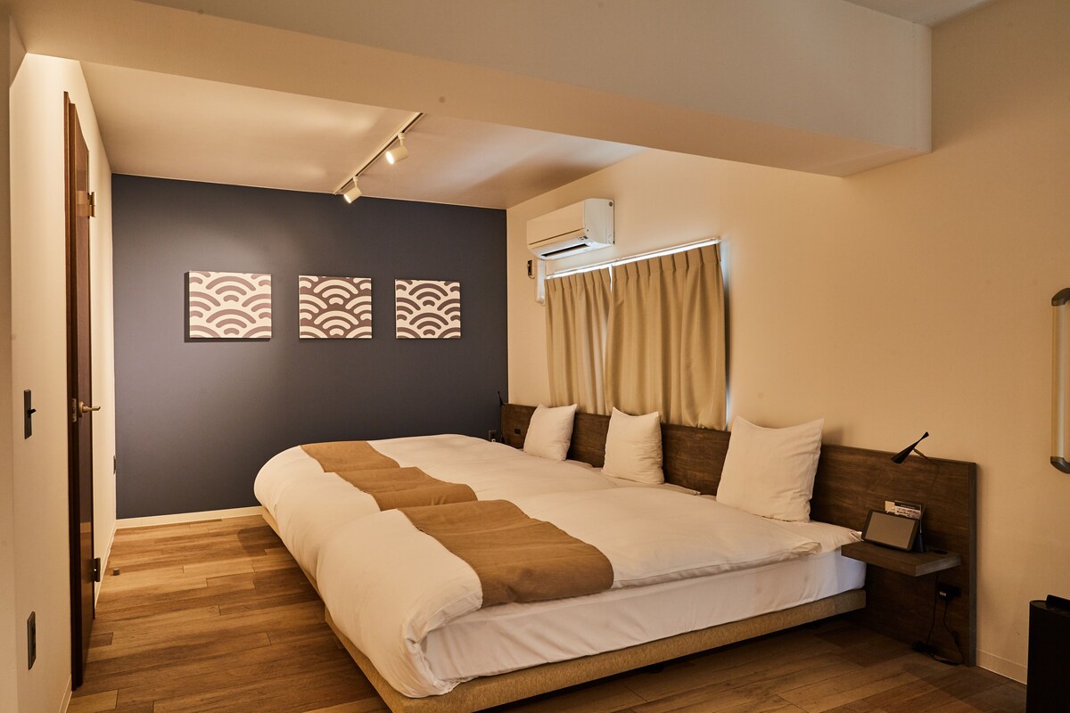A bedroom with a large bed, a bedside table, an air conditioning unit, and a wall-mounted shelf.