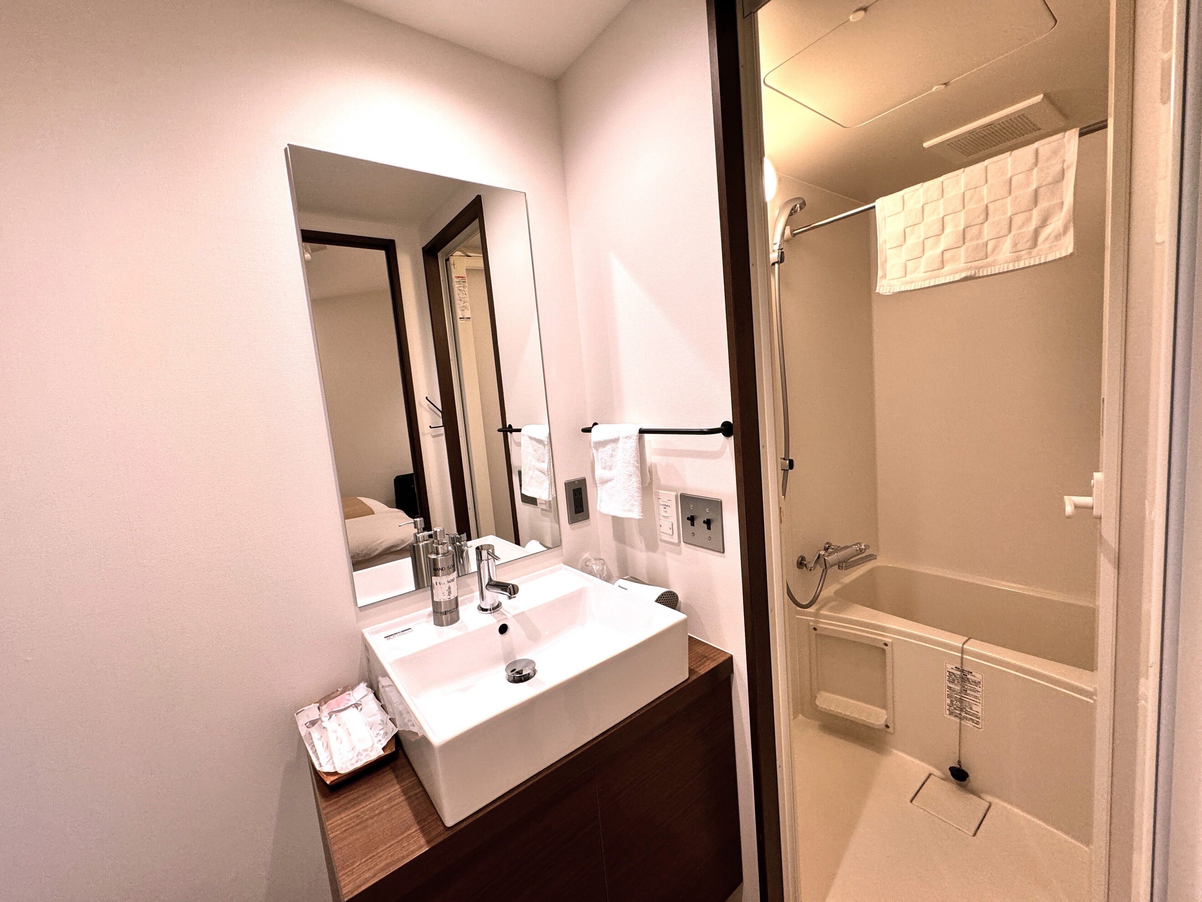 Un bagno moderno con lavandino, specchio e doccia bianchi.