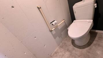 A modern bathroom with a toilet, grab bar, and a towel rack.