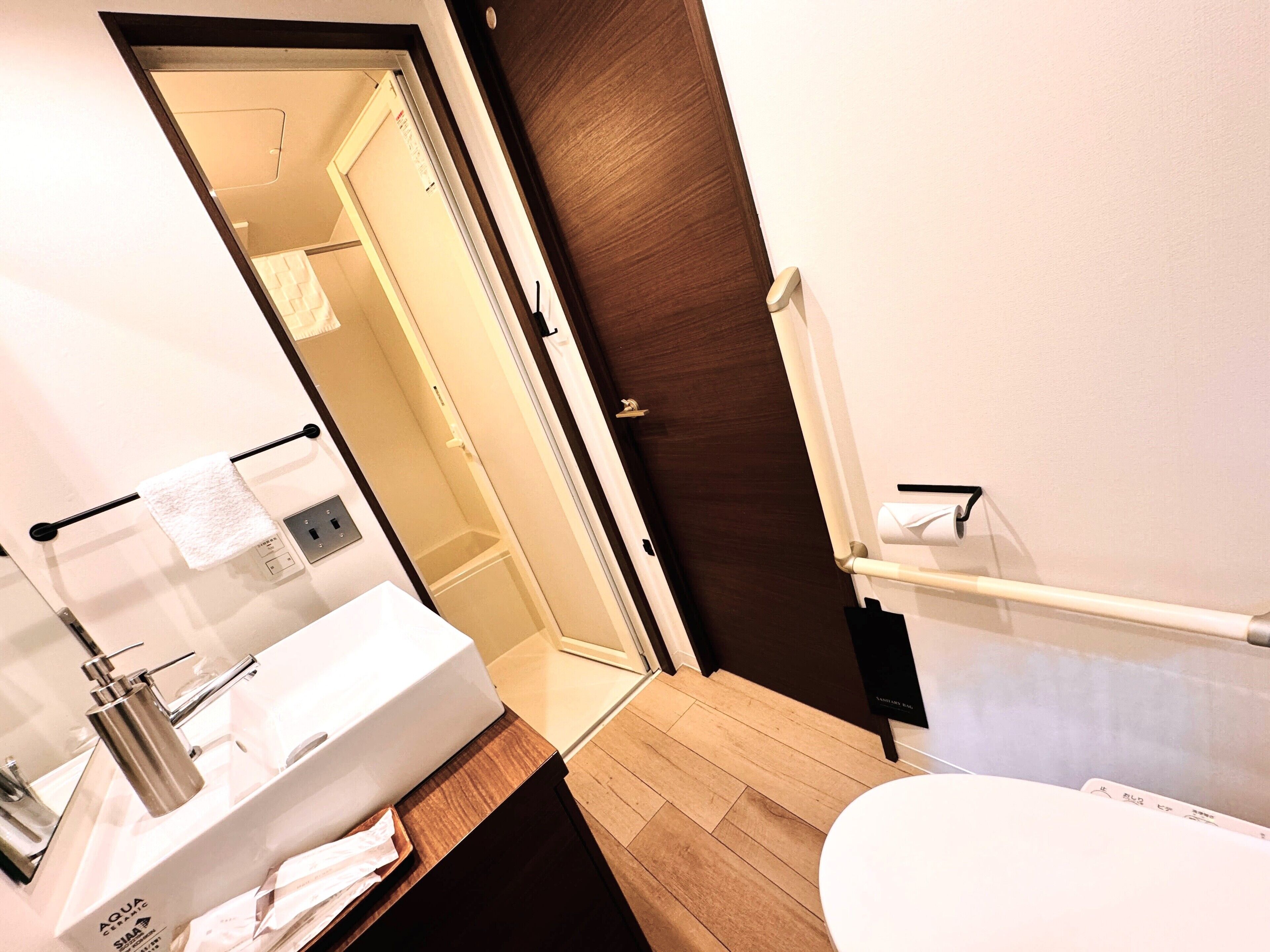 Une salle de bain moderne avec un meuble-lavabo en bois, un lavabo blanc et une cabine de douche en verre.
