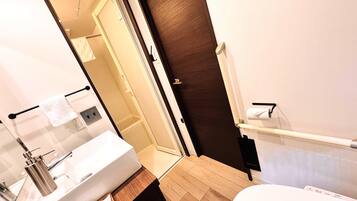 A modern bathroom with a wooden vanity, a white sink, and a glass shower enclosure.