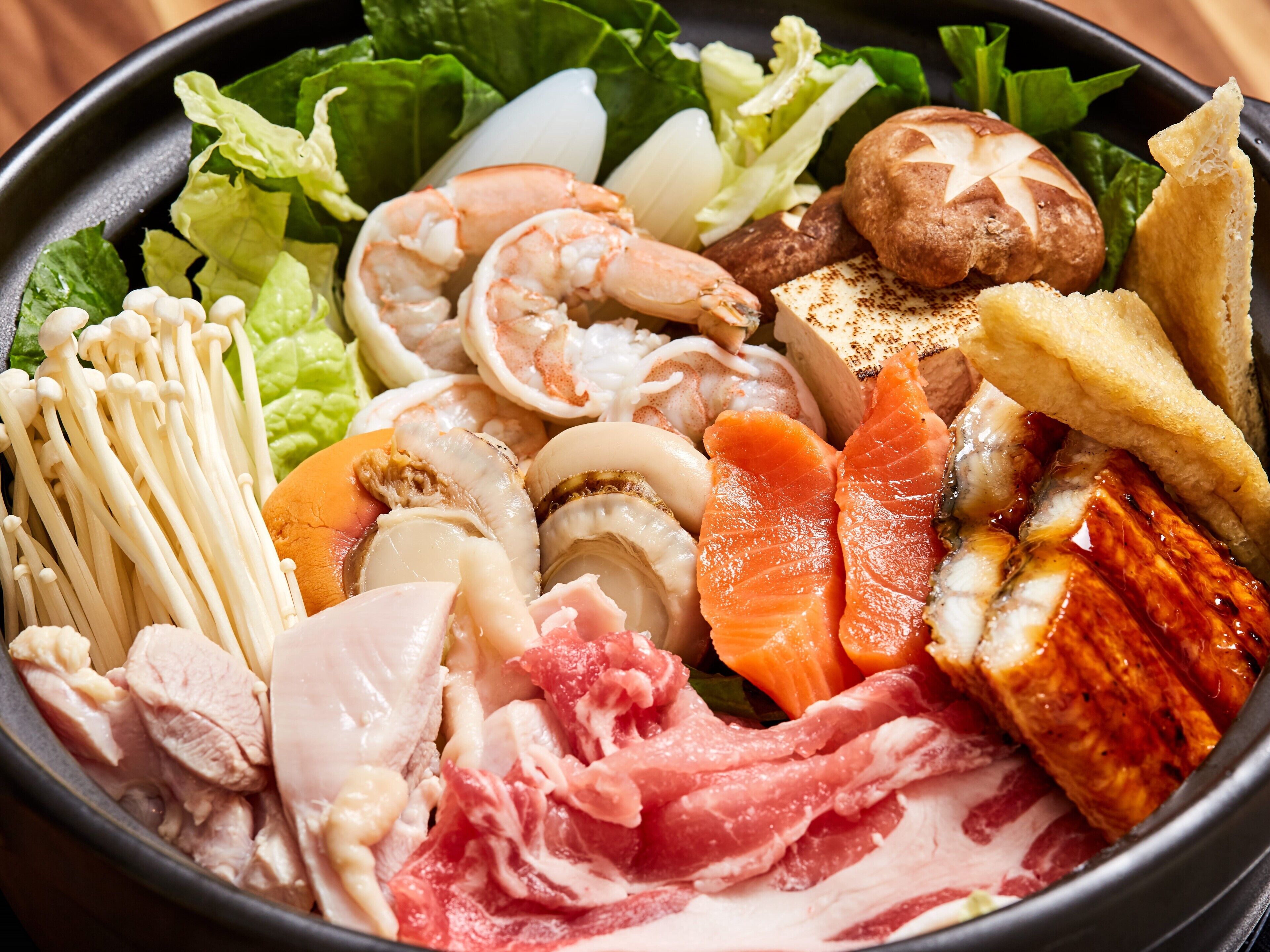 Un assortiment de fruits de mer, notamment des crevettes, du saumon et des champignons, servis sur un lit de laitue.