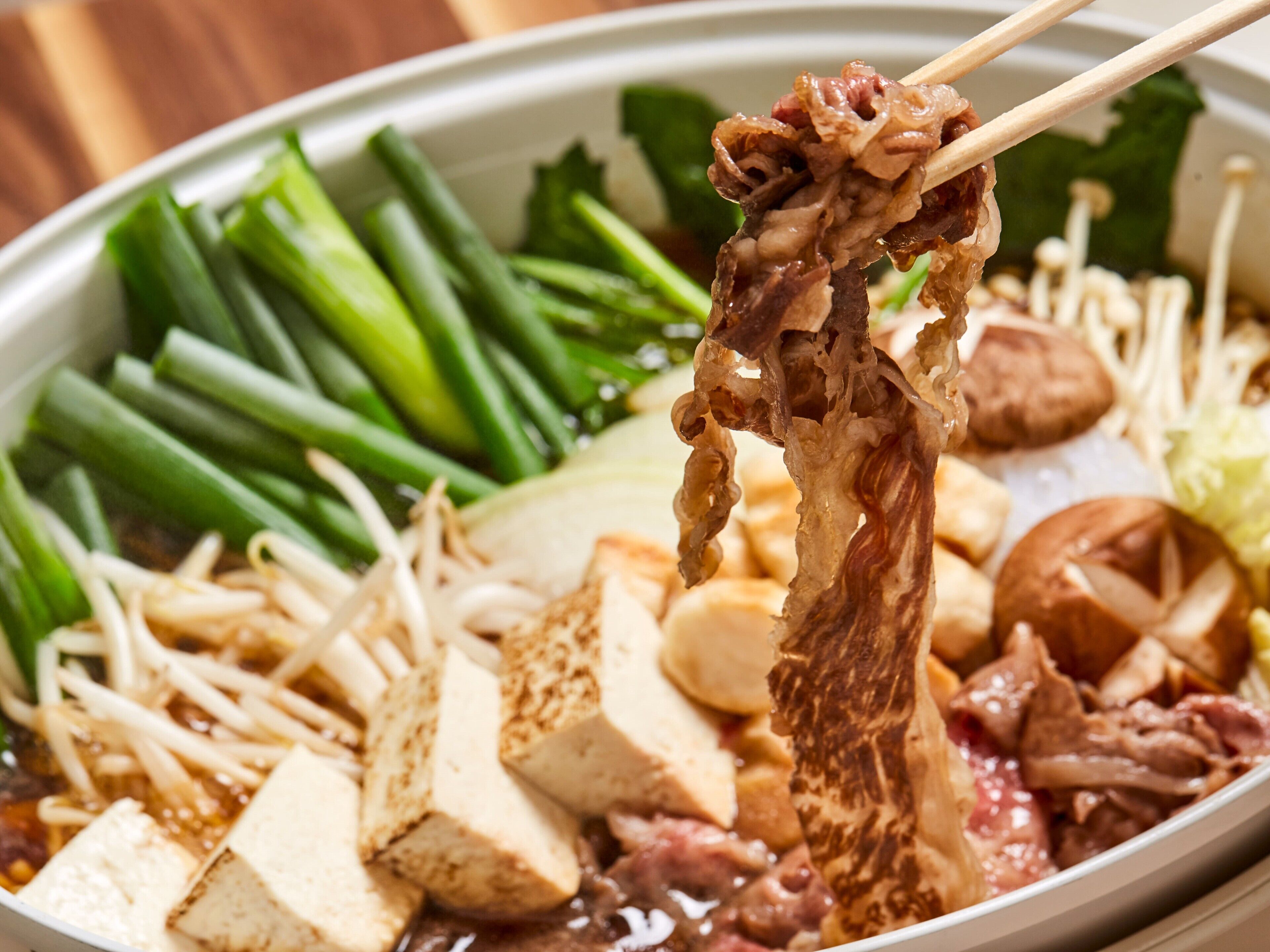 Un bol de soupe de nouilles asiatique, contenant du tofu, des légumes et de la viande.