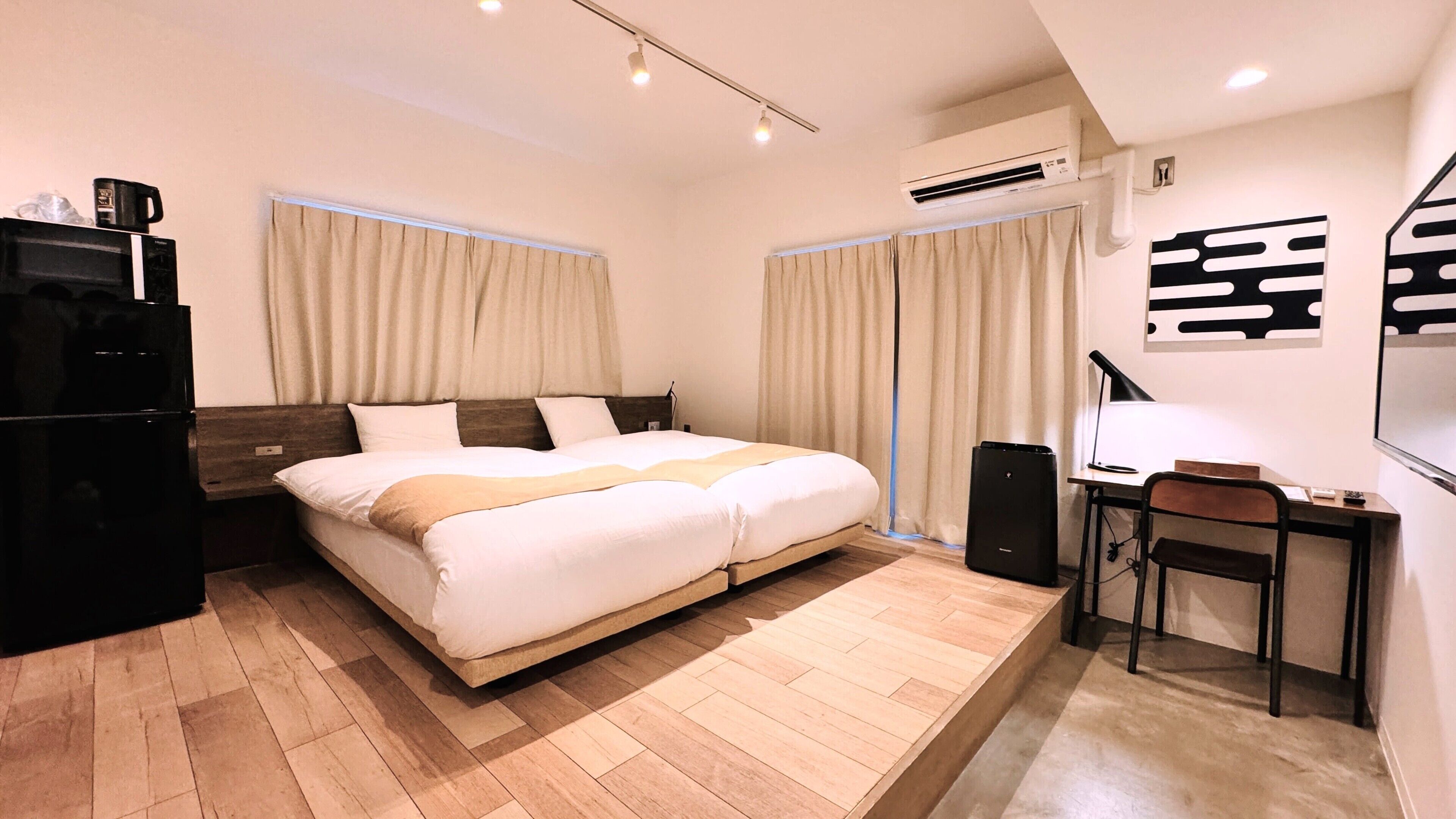 Una habitación de hotel con cama, escritorio, silla, aire acondicionado y televisor.