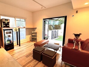 A compact living space with a refrigerator, a small kitchenette, a seating area with a red couch, and a dog on the couch.