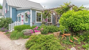 Een charmant huis met een veranda, omringd door weelderige begroeiing en een tuin.