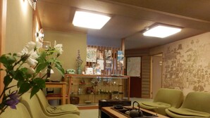 Una sala de estar acogedora con sofás verdes, una mesa de centro de madera y una pequeña zona de cocina con hervidor.
