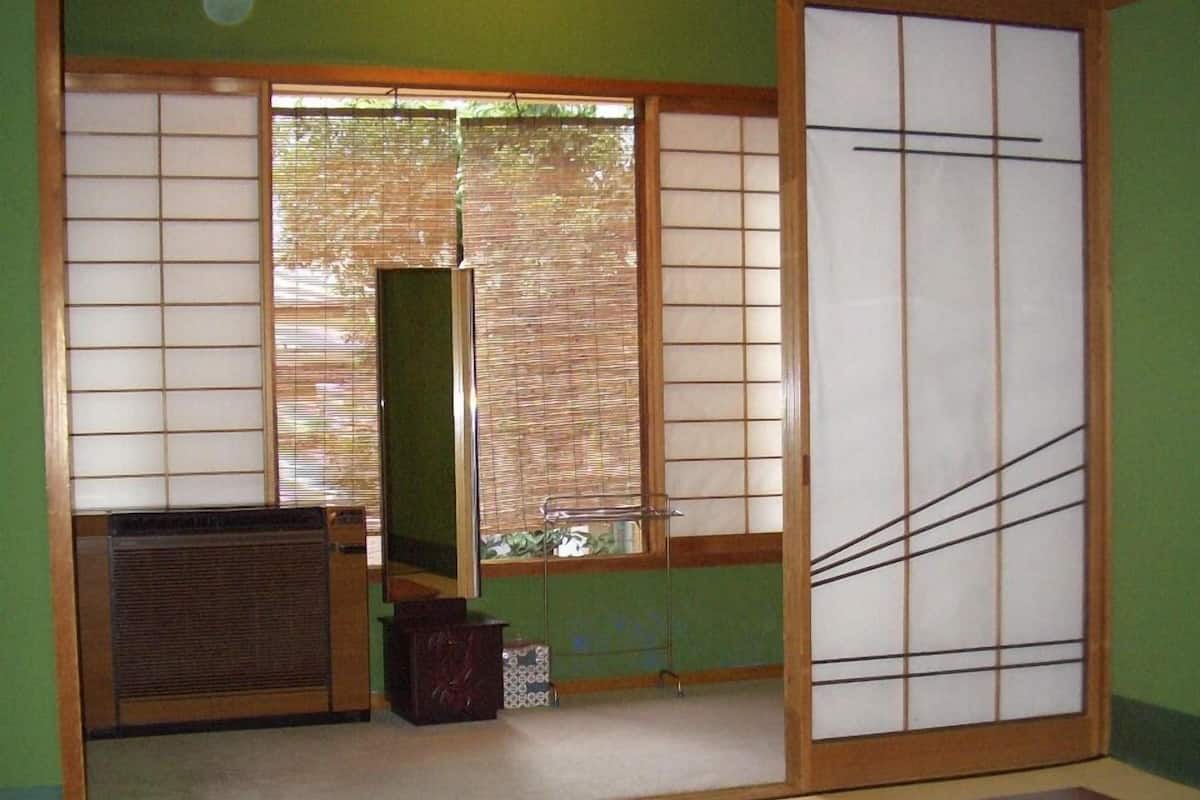 Um quarto japonês tradicional com tatames, portas deslizantes e uma mesa de madeira baixa.