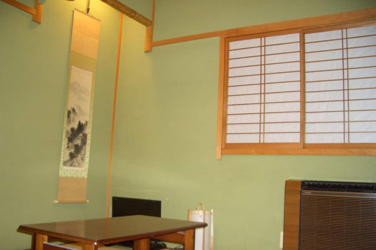 Um quarto japonês tradicional com tatames, uma mesa baixa, um biombos shoji e um radiador.