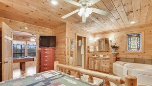 A wooden cabin interior with a bed, a television, a bathroom with a bathtub, and a wooden desk with a chair. - Inspiration Point 1 Bedroom 1 Bathroom Cabin (Sevierville)