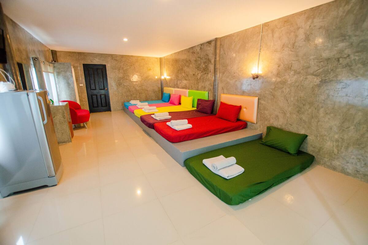 Quarto de hotel com uma cama grande, um sofá pequeno e um frigorífico.