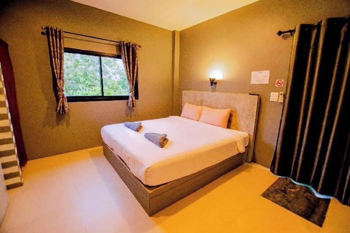 Quarto com cama, janela com cortinas, luminária na parede e porta.