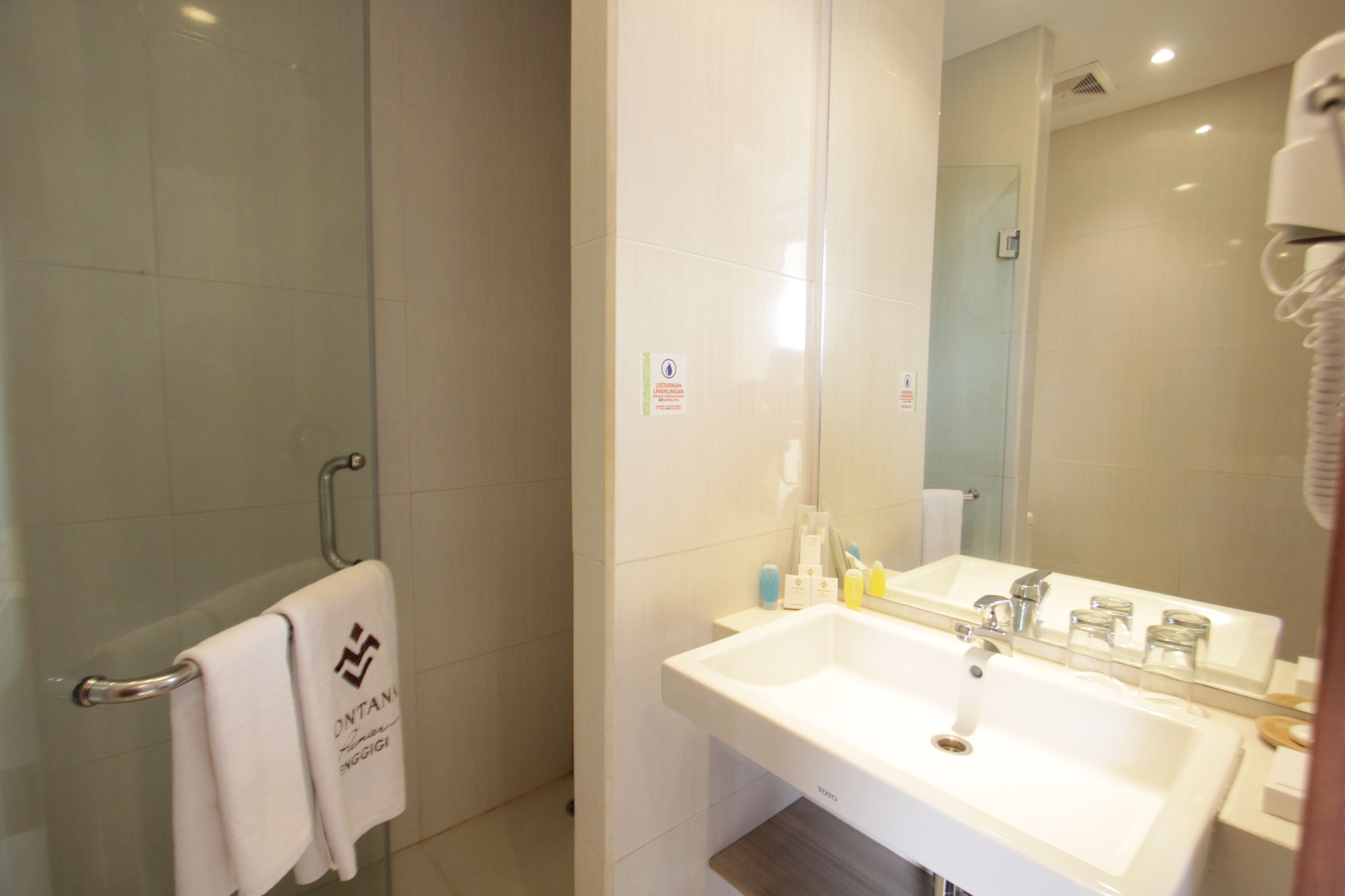 Une salle de bain avec un lavabo blanc, un miroir et une cabine de douche en verre.