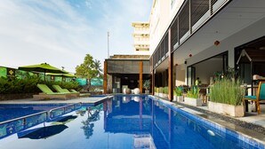Una piscina con sillas de descanso y un edificio con un porche cubierto.
