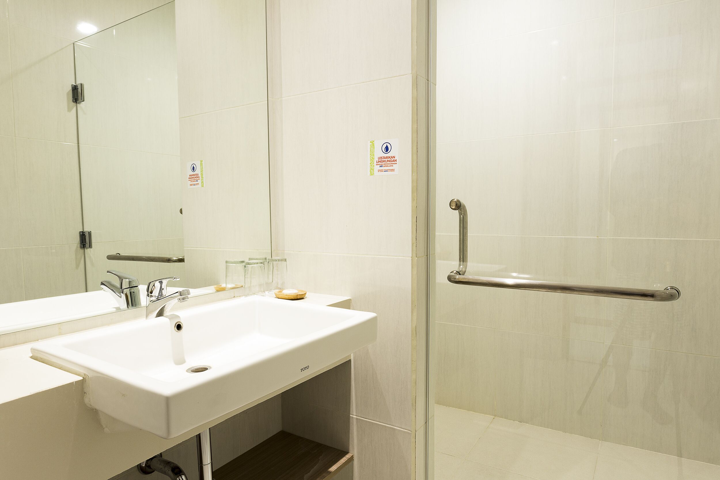 Un baño con lavamanos blanco, espejo y cabina de ducha de vidrio.