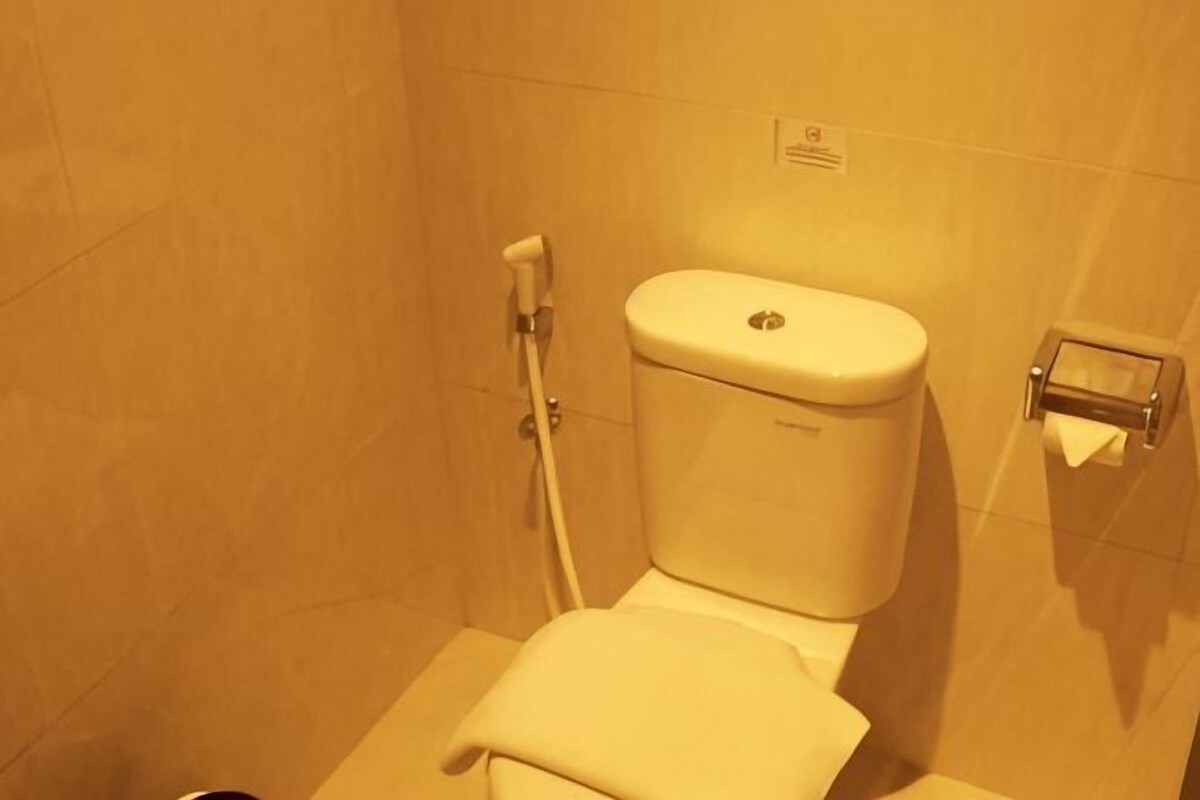 Une salle de bain équipée de toilettes, d’un porte-serviettes et d’un support à papier toilette.