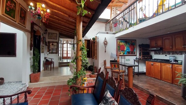 Uma sala de estar ampla com conjunto de jantar, cozinha com armários de madeira e varanda com guarda-corpo.