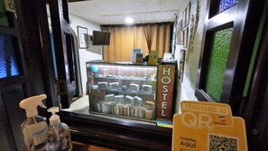 A hotel reception area with a glass display case containing various items, a sign reading "HOSTEL", and a QR code for digital services. - Hostel Santander Aleman Terrace Vista (San Gil)