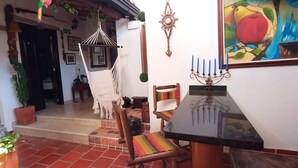 Uma área de pátio aconchegante com uma rede, uma cadeira de madeira e uma mesa.