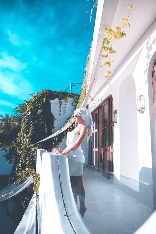 A person standing on a balcony with a view of a building and a clear blue sky.