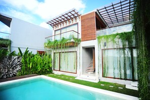 A modern house with a swimming pool, a wooden staircase, and a balcony with greenery.