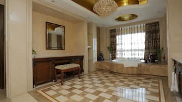 A spacious bathroom with a checkered floor, a large mirror, a bench, and a bathtub.