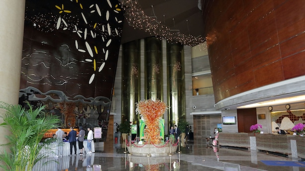 A spacious lobby with a reception desk, potted plants, and a decorative centerpiece. - Arcadia International Hotel (Langfang)
