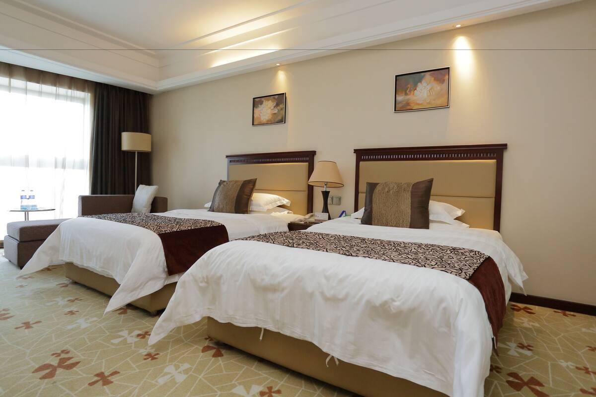 Une chambre d’hôtel avec deux lits, un bureau et une chaise.