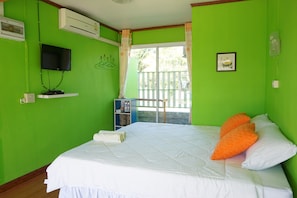 A room with a bed, a television mounted on the wall, a window with curtains, and a small shelf with items. - Thong Hug House Resort (Phu Ruea)
