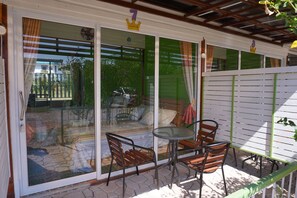A patio with a glass door, a small round table, and two wooden chairs.