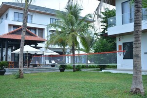 A modern building with a red-tiled roof, outdoor seating, and a volleyball net.