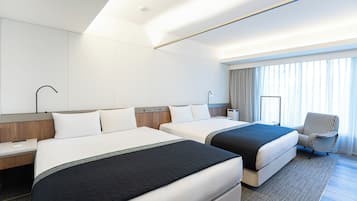 Una habitación de hotel con dos camas, un escritorio, una silla y un ventanal con cortinas.