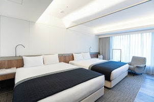 Une chambre d’hôtel avec deux lits, un bureau, une chaise et une grande fenêtre avec des rideaux.
