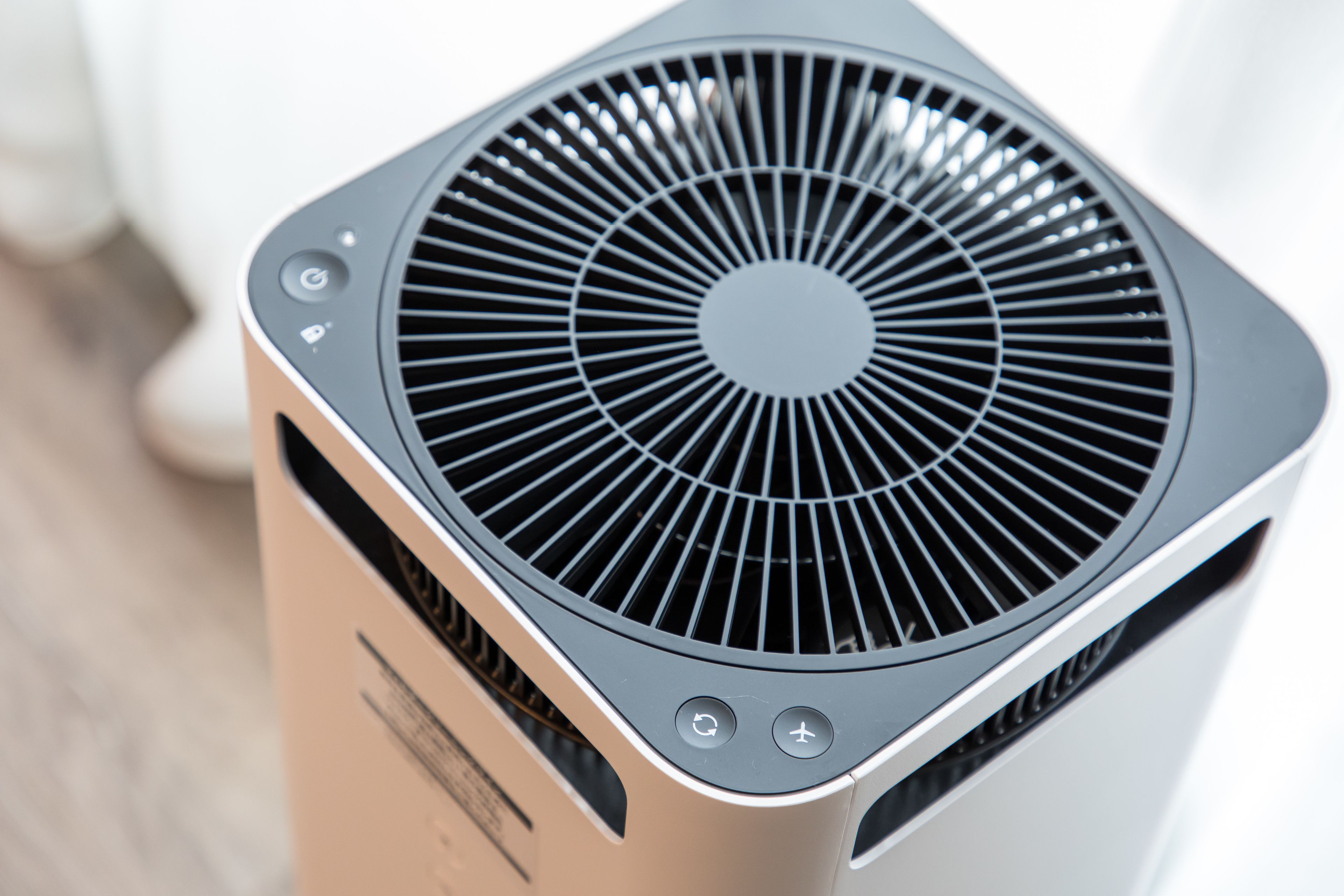 A modern air conditioning unit with a circular vent design and control buttons.