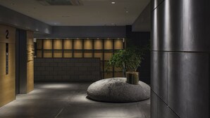 A modern lobby with a stone bench, a potted plant, and a reception area with a number sign.