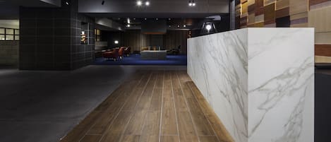 A modern interior with a wooden floor, a marble accent wall, and a seating area with chairs and a sofa.