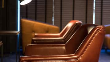 A row of brown leather chairs with a modern design, positioned in a dimly lit room with vertical blinds in the background.