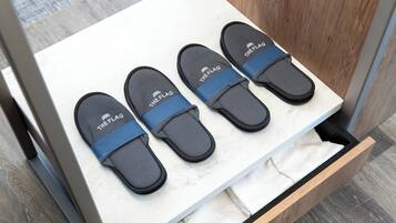 Un cajón con tres pares de pantuflas negras con correas azules etiquetadas como "THE FLAG".