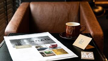 A brown leather chair with a table in front of it. On the table, there is a cup of coffee, a menu, and a business card.
