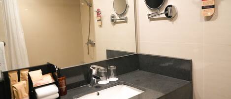 A bathroom with a sink, mirror, and shower.
