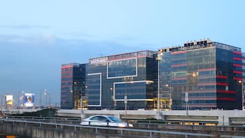 Un hotel moderno con fachada de vidrio, con la señalización 'Savoy Hotel' y 'Expedia', y 'MEGAWORLD' en la esquina superior derecha.