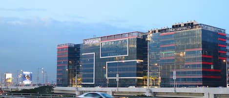 A modern hotel with a glass facade, named 'Savoy Hotel' and 'Expedia' on the signage, and 'MEGAWORLD' on the top right.