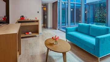 A modern hotel lobby with a wooden reception desk, a teal sofa, and a small round table with a vase of flowers.